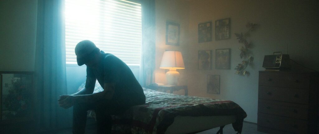 man in black jacket sitting on bed
